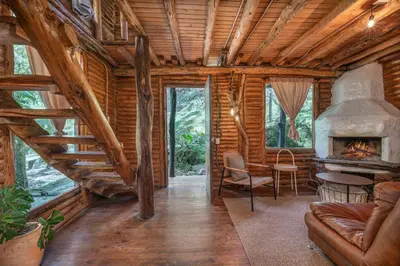 a living room with a fireplace in a log cabin at Cabañas Casa Monte en Santa elena in Medellín