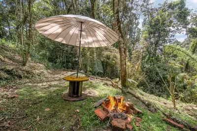an umbrella sitting next to a camp fire at Cabañas Casa Monte en Santa elena in Medellín