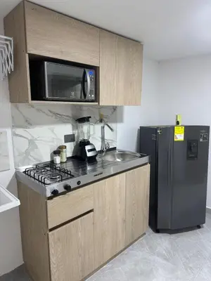 a kitchen with a stove and a microwave and a refrigerator at Villa Loreto Aparta estudio 203 in Medellín
