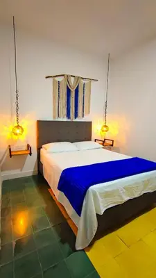 a bedroom with a large bed with blue sheets at Hotel Colonial San Roque in San Roque
