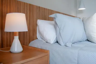 a bed with white pillows and a lamp on a table at Altura y Confort en Envigado in Envigado