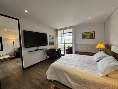a bedroom with a large bed and a flat screen tv at Casagrande Apartahotel in Rionegro