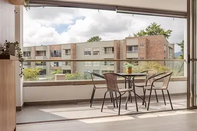 a balcony with a table and chairs and a large window at Casagrande Apartahotel in Rionegro