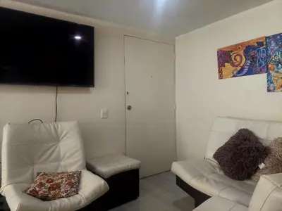 a living room with two chairs and a flat screen tv at Apartamento céntrico en el poblado in Medellín