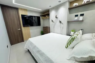 a bedroom with a large white bed and a television at 1B Luxury Apartment San Javier medellin in Medellín