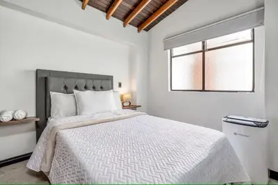 a white bedroom with a large bed with a window at Urban 5th floor Living with AC unit 3Bed3bth no elevator 5 guests max in Envigado