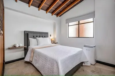 a white bedroom with a bed and a window at Urban 5th floor Living with AC unit 3Bed3bth no elevator 5 guests max in Envigado