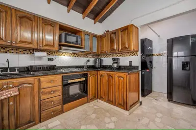 a kitchen with wooden cabinets and a stainless steel refrigerator at Urban 5th floor Living with AC unit 3Bed3bth no elevator 5 guests max in Envigado