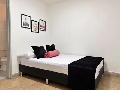 a bed with black and white sheets and pink pillows at Exclusive Group Accomodation in Medellín