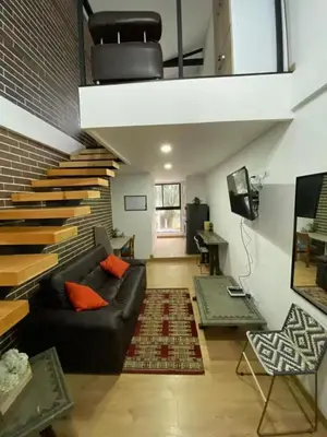 a living room with a black couch and a brick wall at Laureles Garden in Medellín