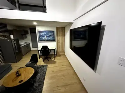 a living room with a table and a tv on a wall at Laureles Garden in Medellín