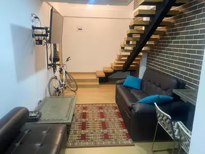 a living room with a leather couch and a staircase at Laureles Garden in Medellín