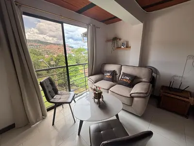 a living room with a couch and a table and a large window at Apartamento Vista Bella en la mitad de Medellin in Medellín