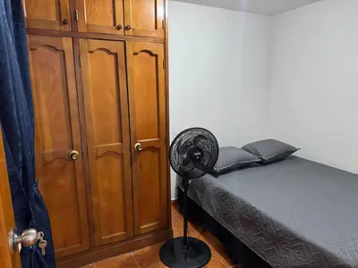 a bedroom with a bed and a fan next to a cabinet at Casa del parque in Bello