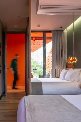 a hotel room with two beds and a person walking into the room at Calle Flora Hotel by Jalo in Medellín