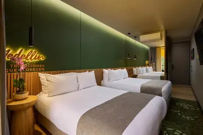 a hotel room with two beds and a green wall at Calle Flora Hotel by Jalo in Medellín