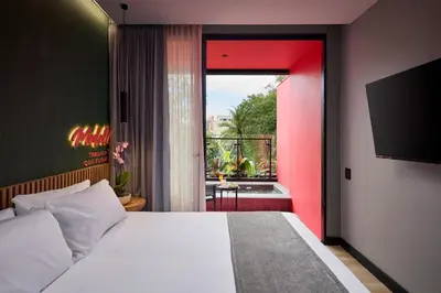 a bedroom with a white bed and a red wall at Calle Flora Hotel by Jalo in Medellín