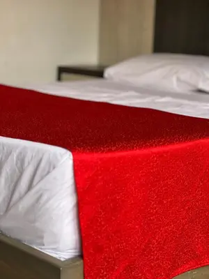 a red blanket on a bed with white sheets at Hotel La Bastida in Marinilla