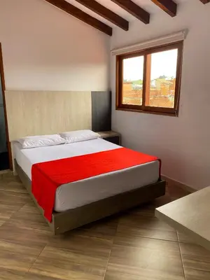 a bedroom with a large bed with a red blanket at Hotel La Bastida in Marinilla