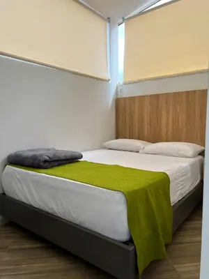 a bedroom with a bed with a green blanket on it at Hotel La Bastida in Marinilla
