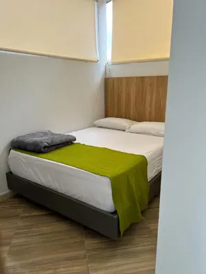 a bedroom with a bed with a green blanket on it at Hotel La Bastida in Marinilla