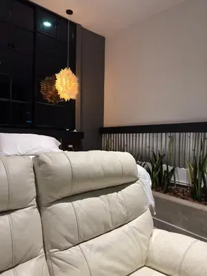 a white couch in a bedroom with a chandelier at Hostel43 in Estación El Salto