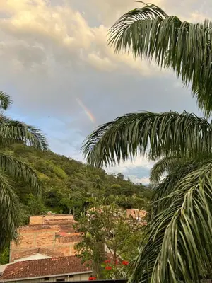a rainbow in the sky over a city with palm trees at La terraza 2 in Ciudad Bolívar