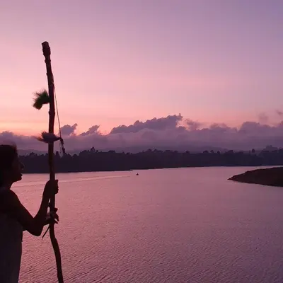 a person holding a pole next to a body of water at El Trebol in Guatapé