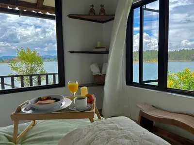 a breakfast table with a bowl of fruit on a bed in a room with windows at El Trebol in Guatapé