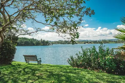 a park bench sitting on the grass near a lake at El Trebol in Guatapé