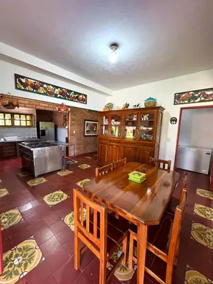 a dining room with a wooden table and a kitchen at Hacienda San Rafael en Jericó, Antioquia in Jericó