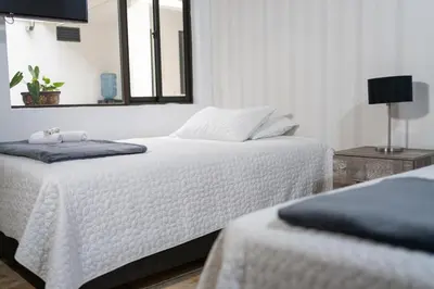 a white bedroom with two beds and a mirror at Casa Laurel Hospedaje Boutique Alojamiento Completo in Medellín