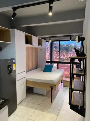 a bedroom with a bed and a large window at Apartaestudio GoldensMary Buenos Aires in Medellín