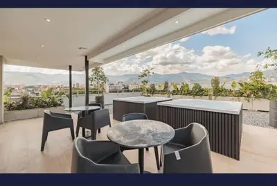 a balcony with tables and chairs and a view of a city at NEW Loft 38 mt in Laureles, AC, Internet, Jacuzzis, 1 Queen Bed & 1 sofabed in Medellín