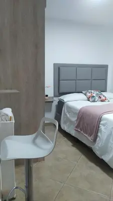 a bedroom with a bed and a white chair at Amoblado en la Estrella in La Estrella
