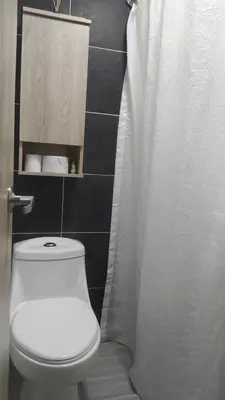 a bathroom with a toilet and a white shower curtain at Amoblado en la Estrella in La Estrella
