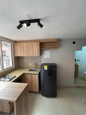 a kitchen with a black refrigerator and wooden cabinets at new apartment in front of the park in Medellín