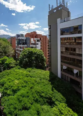 a green hill in a city with buildings at Cozy and Bright Studio Loft in Central Laureles in Medellín
