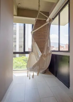 a hammock hanging in a room with large windows at Cozy and Bright Studio Loft in Central Laureles in Medellín