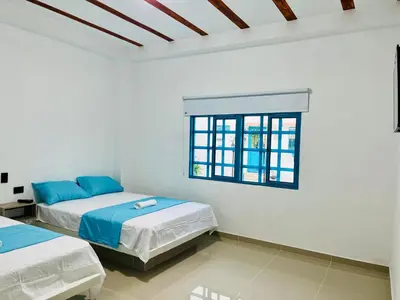 two beds in a white room with a window at Amanecer Santorini in Estación El Salto
