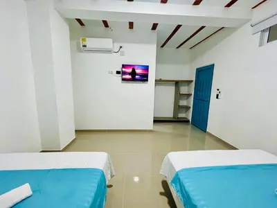 two beds in a room with a tv on the wall at Amanecer Santorini in Estación El Salto