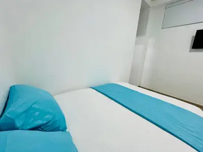 a small bedroom with a bed with blue sheets at Amanecer Santorini in Estación El Salto