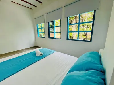 a bedroom with a bed and two windows at Amanecer Santorini in Estación El Salto