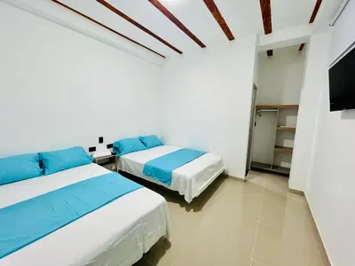 two beds in a white room with a tv at Amanecer Santorini in Estación El Salto