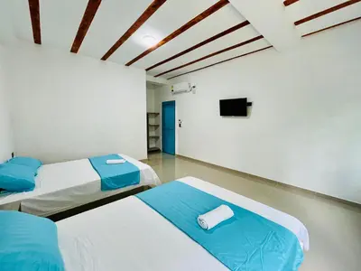 two beds in a room with a tv on the wall at Amanecer Santorini in Estación El Salto