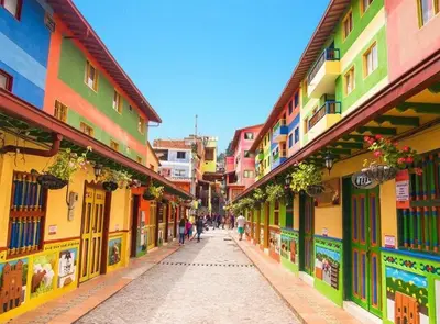 a street with colorful buildings and people walking down the street at MORITZ By MONTE GANDOLFO in Chiquinquirá