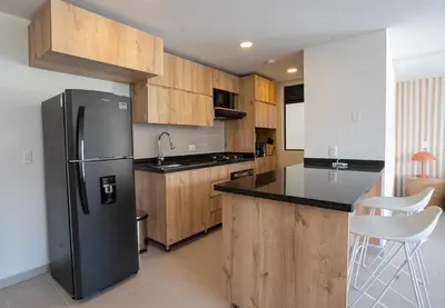 a kitchen with a black refrigerator and wooden cabinets at Elegant apt in Laureles The best area in Medellin in Medellín