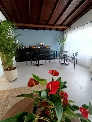 a room with chairs and a table with red flowers at Bluelux Med - B&B in Medellín