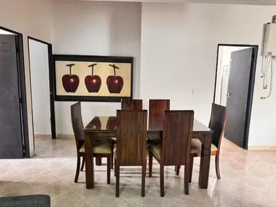 a dining room table and chairs with an apple painting on the wall at Apartamentos compostela in Medellín