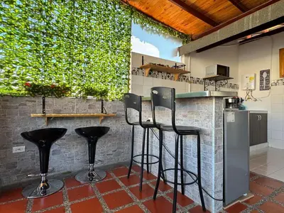 a kitchen with black bar stools in front of a counter at Apartamentos compostela in Medellín